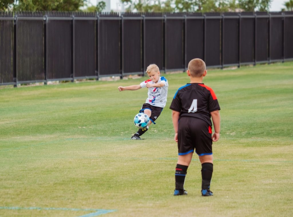 2-boys-playing-soccer-on-green-grass-field-during-daytime-sx906uyeswi